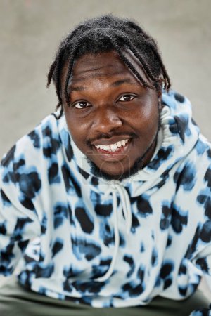 Téléchargez les photos : Portrait vertical rapproché de jeune homme noir portant un sweat à capuche et souriant à la caméra - en image libre de droit