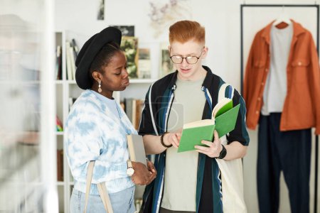 Photo for Waist up portrait of two young people looking at used books in thrifting shop or swap event - Royalty Free Image