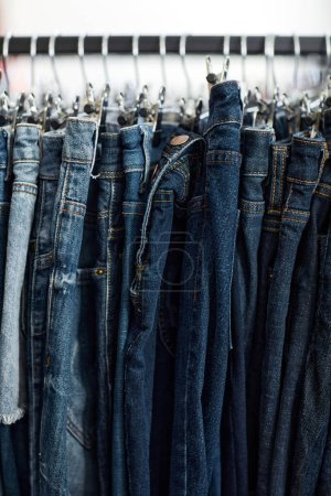 Photo for Vertical background image of blue denim jeans in row on clothing rack at thrift shop - Royalty Free Image