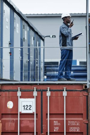 Téléchargez les photos : Portrait graphique d'un ouvrier debout sur des conteneurs dans des docks d'expédition - en image libre de droit