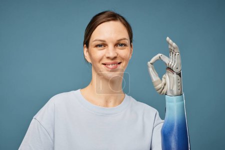Téléchargez les photos : Joyeuse jeune femme avec la main bionique montrant ok signe - en image libre de droit