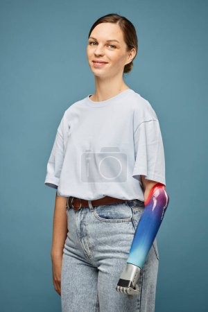 Téléchargez les photos : Portrait de jeune femme souriante en jeans et t-shirt blanc serrant poing prothétique - en image libre de droit