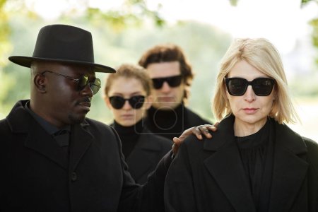 Foto de Retrato mínimo de una mujer vestida de negro en la ceremonia funeraria al aire libre con un amigo reconfortándola - Imagen libre de derechos