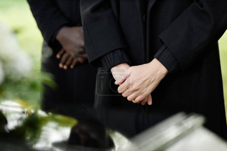 Photo for Close up of person in black standing by coffin at outdoor funeral ceremony, copy space - Royalty Free Image