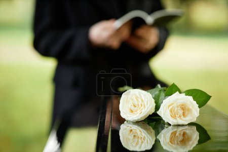 Photo for Closeup of two white roses on coffin at outdoor funeral ceremony, copy space - Royalty Free Image