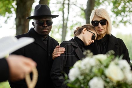 Téléchargez les photos : Portrait de mère et fille embrassant lors d'une cérémonie funéraire en plein air et pleurant ensemble - en image libre de droit