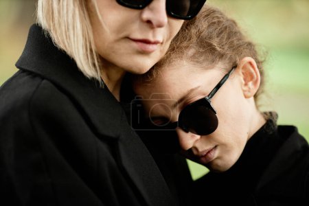 Téléchargez les photos : Gros plan de la mère et de la fille embrassant à la cérémonie funéraire en plein air et pleurant ensemble - en image libre de droit