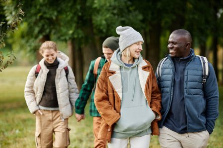 Téléchargez les photos : Portrait taille haute d'un groupe d'amis souriants profitant d'une promenade dans la forêt d'automne - en image libre de droit