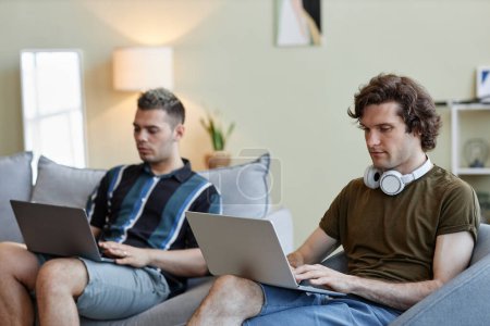 Porträt zweier junger Männer, die zusammen leben und Computer von zu Hause aus nutzen