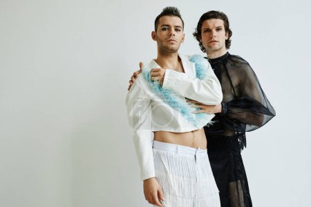 Téléchargez les photos : Portrait de deux jeunes non binaires portant des tenues féminines posant contre le blanc dans un studio de mode, espace de copie - en image libre de droit