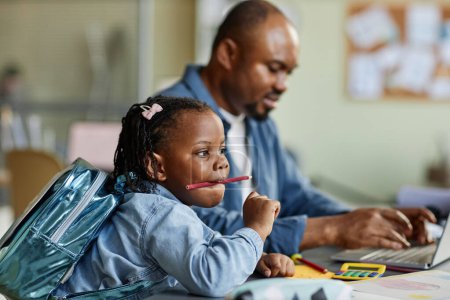 Photo for Side view portrait of cute black girl playing with pencils while father working in background - Royalty Free Image