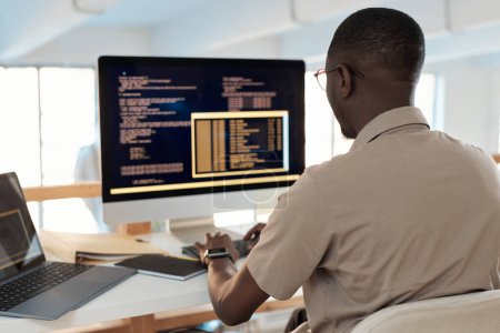 Foto de Desarrollador de software negro trabajando en la computadora, probando el código de la nueva aplicación - Imagen libre de derechos