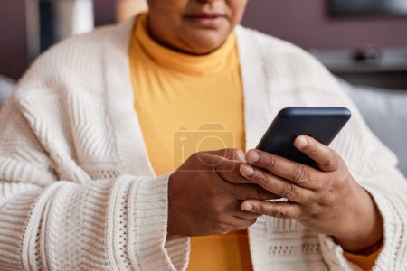 Foto de Primer plano de la mujer mayor negro sosteniendo teléfono inteligente y charlando en línea en casa - Imagen libre de derechos