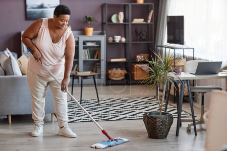 Téléchargez les photos : Portrait complet de femmes noires âgées qui nettoient les planchers tout en appréciant le nettoyage de la maison, espace de copie - en image libre de droit