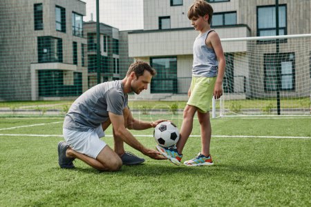 Foto de Retrato de vista lateral de padre joven enseñando fútbol hijo en corte al aire libre, espacio de copia - Imagen libre de derechos
