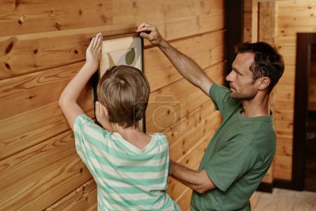 Téléchargez les photos : Portrait latéral du père et du fils accroché à un mur en bois dans une nouvelle maison - en image libre de droit