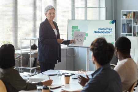 Photo for Portrait of senior businesswoman giving presentation in office while leading meeting with team, copy space - Royalty Free Image