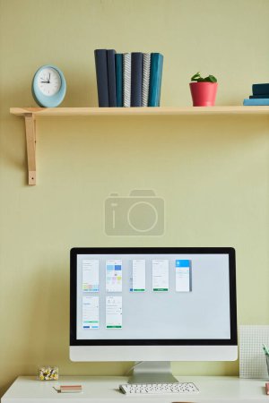 Photo for Vertical background image of minimal home office setup with computer screen and planning charts against pastel yellow wall - Royalty Free Image