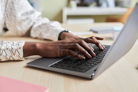 Téléchargez les photos : Gros plan d'une jeune femme noire méconnaissable utilisant un ordinateur portable et tapant sur le clavier - en image libre de droit