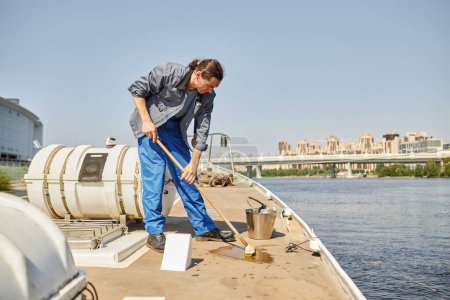 Photo for Full length portrait of sailor washing floors on boat or yacht in sunlight, copy space - Royalty Free Image
