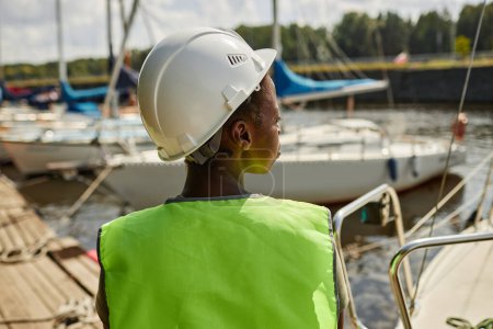 Téléchargez les photos : Vue arrière du travailleur féminin portant un casque de sécurité dans les quais de yacht, espace de copie - en image libre de droit