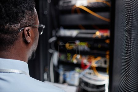 Photo for Back view of black system engineer working with server cabinet in data center, copy space - Royalty Free Image
