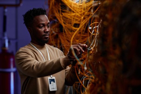 Photo for Waist up portrait of black young man as system administrator setting up server network and doing maintenance - Royalty Free Image