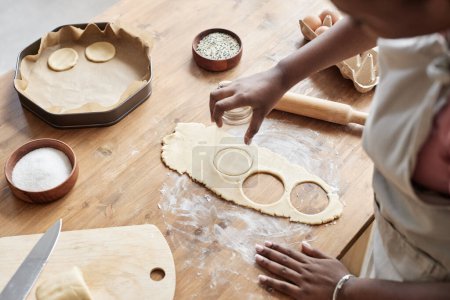 Téléchargez les photos : Portrait recadré d'une femme noire faisant des pâtisseries maison et coupant des formes de biscuits sur un comptoir de cuisine en bois, espace de copie - en image libre de droit