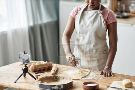 Foto de Imagen recortada de mujer negra horneando pastelería casera en la cocina casera con la cámara del teléfono inteligente grabación de vídeo o transmisión en vivo, espacio de copia - Imagen libre de derechos
