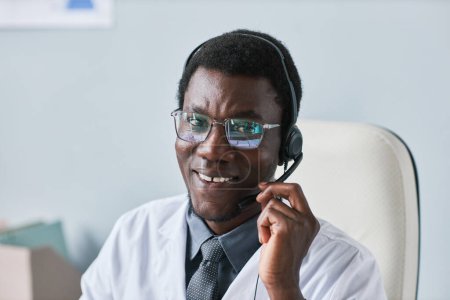 Photo for Portrait of young black doctor wearing headset and smiling at camera in office - Royalty Free Image