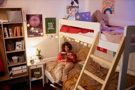Téléchargez les photos : Portrait de deux étudiantes profitant d'une soirée relaxante sur lit superposé dans un dortoir, espace de copie - en image libre de droit
