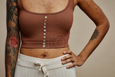 Téléchargez les photos : Gros plan de femme noire tatouée posant avec confiance avec la main sur la hanche, réelle mise au point de la texture de la peau - en image libre de droit
