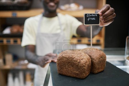 Foto de Panadero poniendo panes sin gluten en escaparate de la tienda - Imagen libre de derechos