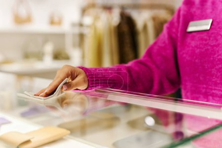 Foto de Primer plano del gerente de ventas limpiando el mostrador de vidrio en una boutique de lujo mientras prepara la tienda para abrir, copiar espacio - Imagen libre de derechos