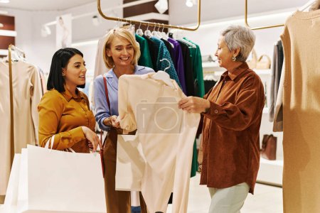 Photo for Group of happy women shopping for clothes in luxury boutique and looking at blouses - Royalty Free Image
