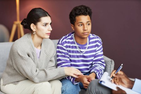 Foto de Preocupada madre y su hijo adolescente acudieron al psicólogo adolescente para discutir los ataques de pánico - Imagen libre de derechos