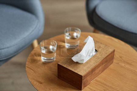 Téléchargez les photos : Boîte en papier tissu et deux verres d'eau sur la table dans le bureau du psychologue - en image libre de droit