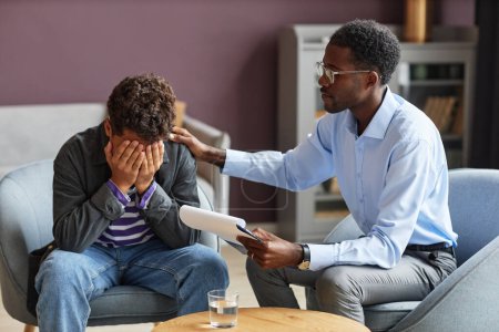 Photo for School psychologist supporting teenage boy crying after getting bullied - Royalty Free Image