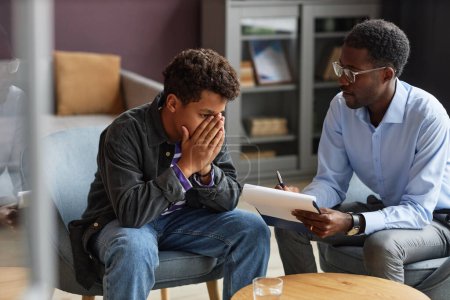 Téléchargez les photos : Adolescent garçon pleurer lors du partage son problèmes avec adolescent psychologue - en image libre de droit