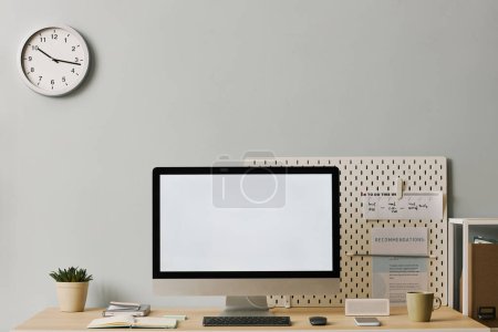 Foto de Imagen de fondo de la computadora con pantalla blanca en blanco en el escritorio en la configuración mínima de la oficina en casa con reloj analógico en la pared de pastel - Imagen libre de derechos