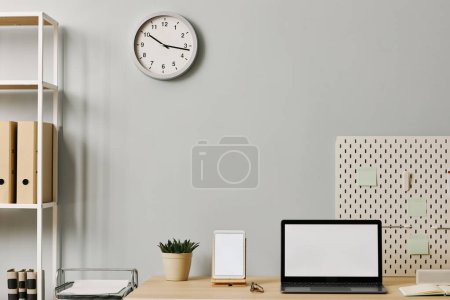 Photo for Minimal office setup with laptop screen mockup on desk by pastel blue wall, copy space - Royalty Free Image