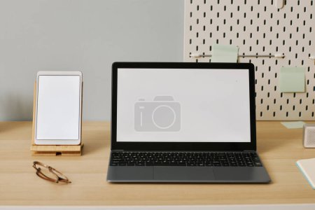 Foto de Imagen de fondo del portátil abierto con maqueta de pantalla blanca en el escritorio en el lugar de trabajo - Imagen libre de derechos