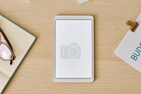 Foto de Vista superior mínima de la tableta digital con maqueta de pantalla blanca en el escritorio de madera clara, espacio de copia - Imagen libre de derechos