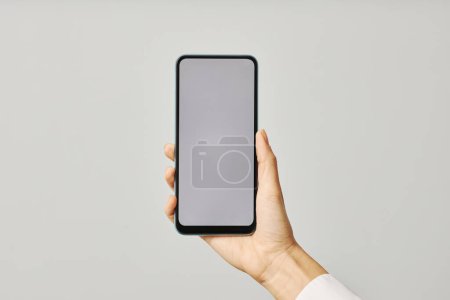 Téléchargez les photos : Gros plan minimaliste de la main féminine tenant smartphone avec écran vierge mock up contre blanc - en image libre de droit