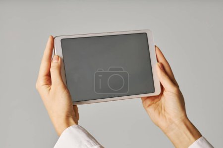 Foto de Primer plano de las manos femeninas sosteniendo la tableta con pantalla en blanco sobre fondo blanco - Imagen libre de derechos