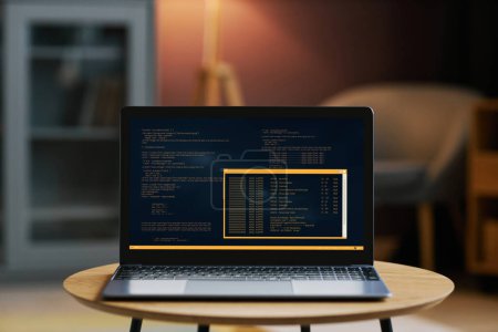 Photo for Background image of open laptop with code on screen in dim home interior - Royalty Free Image