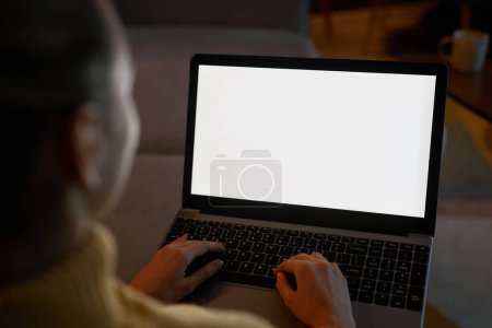 Foto de Primer plano de la mujer que utiliza el ordenador portátil con pantalla blanca en el entorno de la casa oscura, espacio de copia - Imagen libre de derechos