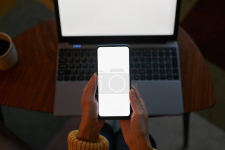 Photo for Top view closeup of young woman using laptop and smartphone with white screen mockups in dark - Royalty Free Image