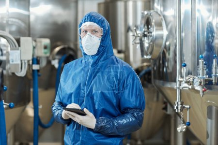 Photo for Waist up portrait of male worker wearing protective suit looking at camera in chemical factory workshop - Royalty Free Image