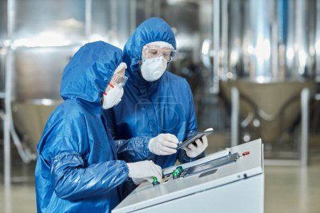 Photo for Side view portrait of two workers using control panel while operating equipment at factory - Royalty Free Image